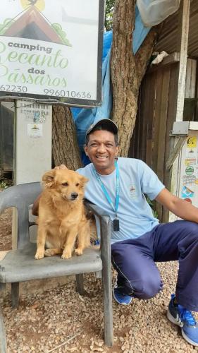 a man sitting on a bench with a dog at CAMPING RECANTO DOS PÁSSAROS in Chapada dos Guimarães