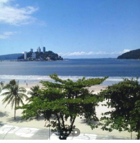 uma praia com palmeiras e o oceano e uma cidade em Aconchego a Beira Mar em São Vicente