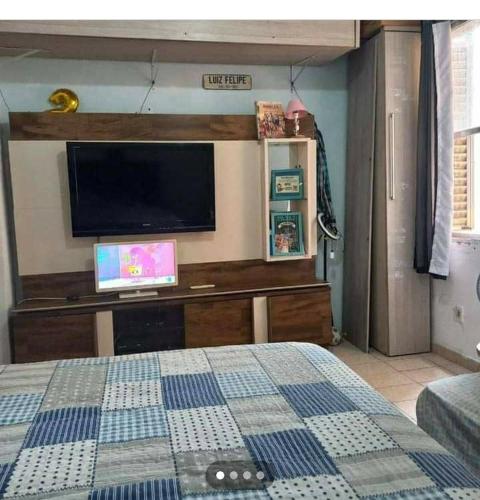 um quarto com uma cama e uma televisão na parede em Aconchego a Beira Mar em São Vicente