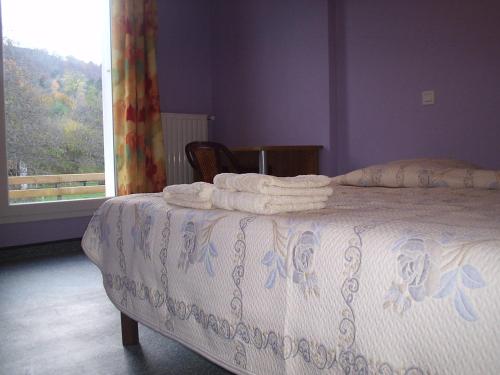 een slaapkamer met een bed met een witte sprei en een raam bij le moulin in Le Monastier sur Gazeille