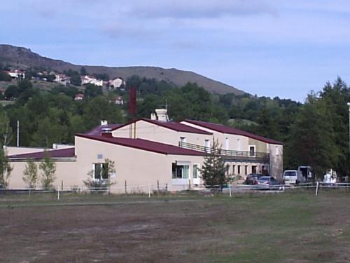 een groot wit gebouw met een berg op de achtergrond bij le moulin in Le Monastier sur Gazeille
