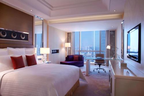 ein Hotelzimmer mit einem großen Bett und einem Schreibtisch in der Unterkunft Guangzhou Marriott Hotel Tianhe in Guangzhou