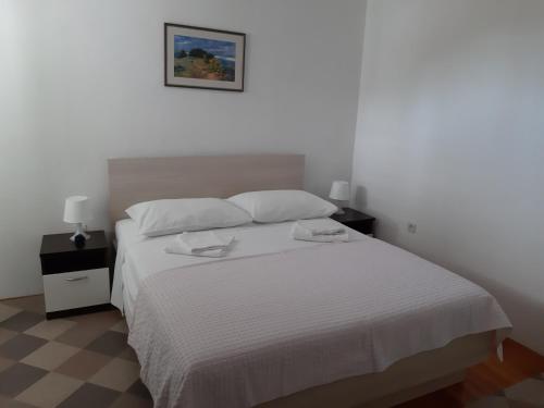ein Schlafzimmer mit einem weißen Bett und zwei Nachttischen in der Unterkunft Apartments by the sea Tisno, Murter - 17716 in Tisno