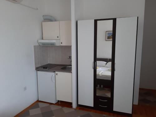 eine kleine Küche mit weißen Schränken und einem Spiegel in der Unterkunft Apartments by the sea Tisno, Murter - 17716 in Tisno