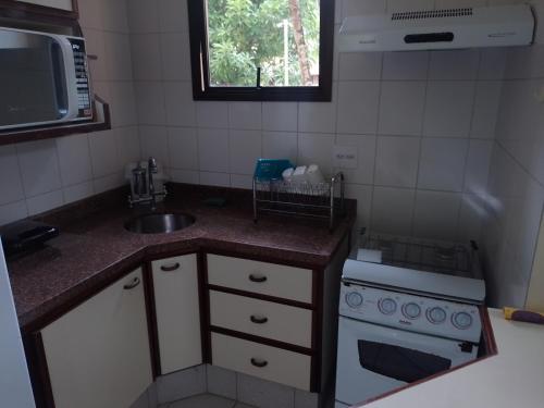 uma pequena cozinha com um lavatório e um fogão em Riviera Green Residence 232 em Bertioga