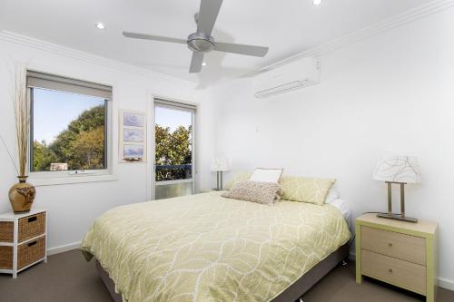 a white bedroom with a bed and a window at Swan Lake Retreat in Berrara