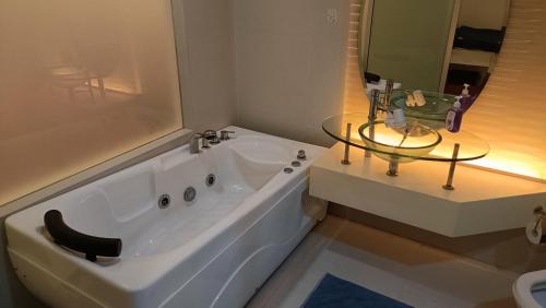 a bathroom with a tub and a glass table next to a sink at Cozy Pertama Residency KL Homestay in Kuala Lumpur