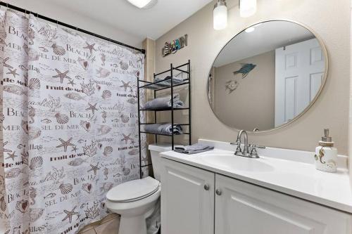 y baño con lavabo, espejo y aseo. en 2 Bed 1 Bath Condo By Beach & Entertainment en South Padre Island