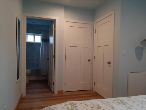 a bedroom with two white doors and a bathroom at Alki Beach Cottage, NEW, 2 bedrooms, 2 bathrooms, near beach, AC, WD, Parking in Seattle