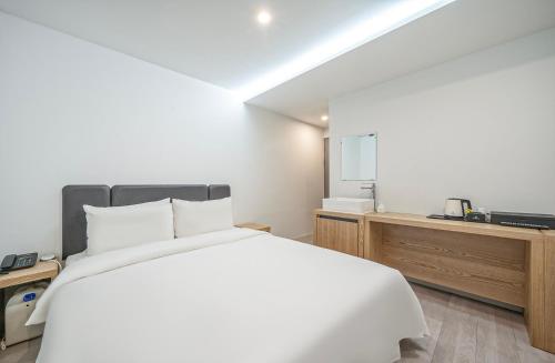 1 dormitorio con 1 cama blanca grande y vestidor en Namuneulno hotel, en Busan