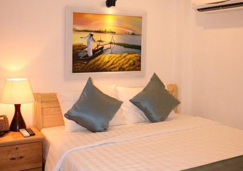 a bedroom with a bed with a picture on the wall at Saigoneer Hotel in Ho Chi Minh City
