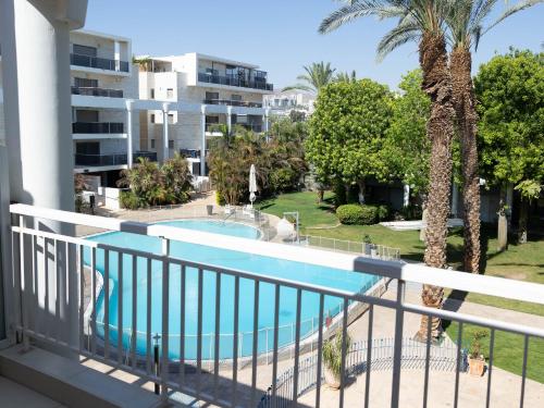 un balcon avec une piscine et un bâtiment dans l'établissement FishaRent Luxury Royal Park Suites, à Eilat