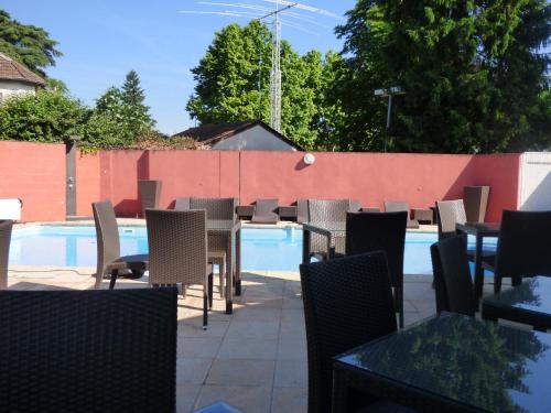 een patio met tafels en stoelen naast een zwembad bij Cit'Hotel Escatel in Mâcon