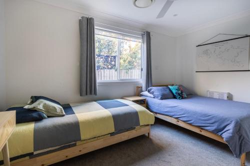 a bedroom with two beds and a window at A Wave from it All in Berrara