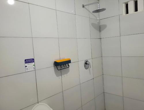 ein weiß gefliestes Bad mit einem WC und einer Dusche in der Unterkunft Beverly Residence in Praya