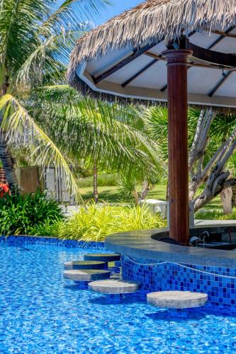 a resort swimming pool with a umbrella and palm trees at Wyndham Grand KN Paradise Cam Ranh in Cam Ranh