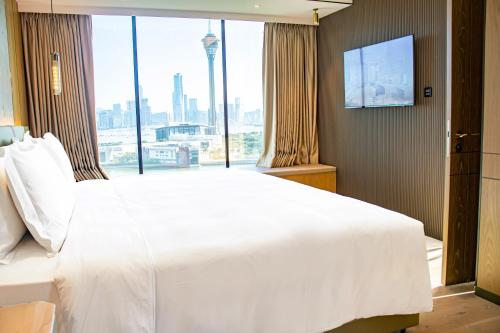 a bedroom with a large white bed and a large window at YOHO Treasure Island Hotel in Macau