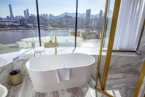 uma banheira na casa de banho com uma grande janela em YOHO Treasure Island Hotel em Macau