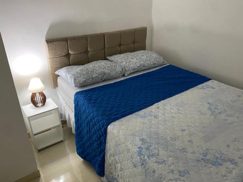 a bedroom with a bed with a blue comforter at Apartamento Vilage na Praia de Armação Salvador in Salvador