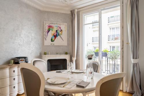 une salle à manger blanche avec une table et une cheminée dans l'établissement Appartement de la Coppée - Welkeys, à Paris