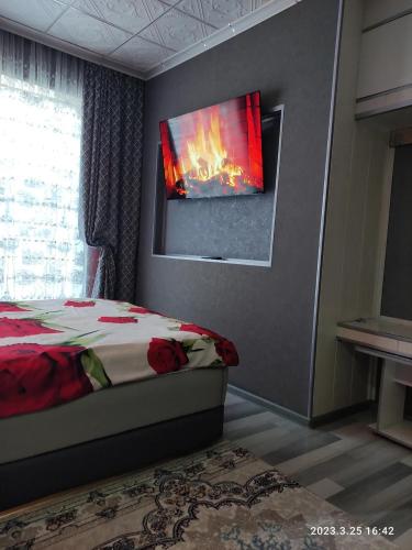 a bedroom with a bed with a tv on the wall at Komfort Lux Centre Karakol in Karakol