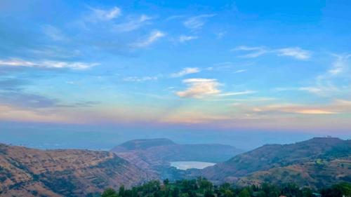a rainbow in the sky over a mountain range at Tabletop Villa Standard - 3 in Panchgani