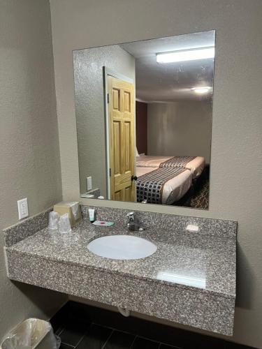 a bathroom with a sink and a mirror and a bed at Westbridge Inn and Suite in Centerville