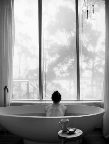 a man sitting in a bath tub looking out a window at Baragoola Retreat - Luxury Waterfront Property in Sandford