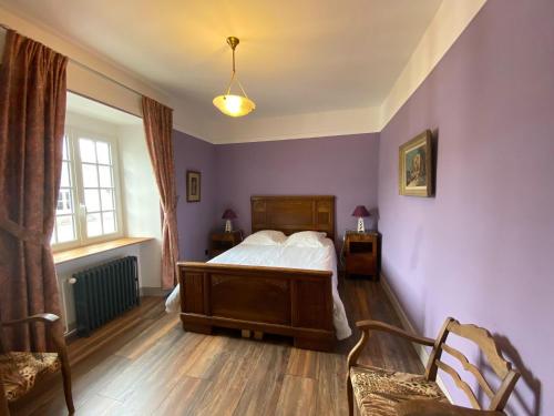 1 dormitorio con paredes moradas, 1 cama y 2 sillas en Comfortable holiday apartment on the 2nd floor of an elegant manor house, en Coutances