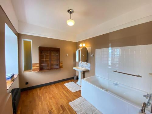 La salle de bains est pourvue d'une grande baignoire et d'un lavabo. dans l'établissement Comfortable holiday apartment on the 2nd floor of an elegant manor house, à Coutances