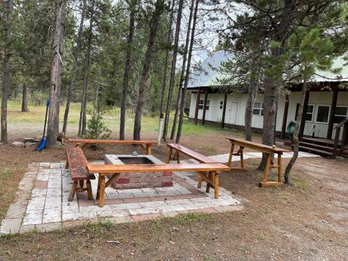two wooden benches and a picnic table in a park at Grandma's Home in the Woods. Yellowstone in Island Park