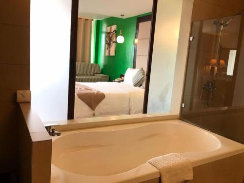 a bathroom with a bath tub and a bedroom at Coron Gateway Hotel & Suites in Coron