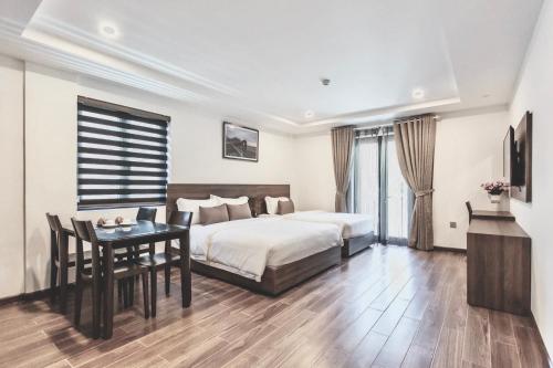 a bedroom with a bed and a table and a desk at La Sera Suites Nha Trang in Nha Trang