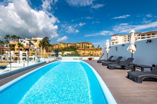 a swimming pool with chaise lounge chairs next to a building at Marina Cabo Plaza Town & Beach Condos in Cabo San Lucas