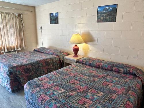 a hotel room with two beds and a lamp at Road Runner Motel Merritt BC in Merritt
