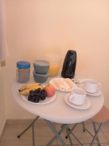 a white table with a plate of fruit and coffee cups at Hospedaria genivaldo in Santo Amaro
