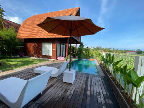 a wooden deck with an umbrella and a swimming pool at Bhumi Lovina Residence & Villa in Singaraja