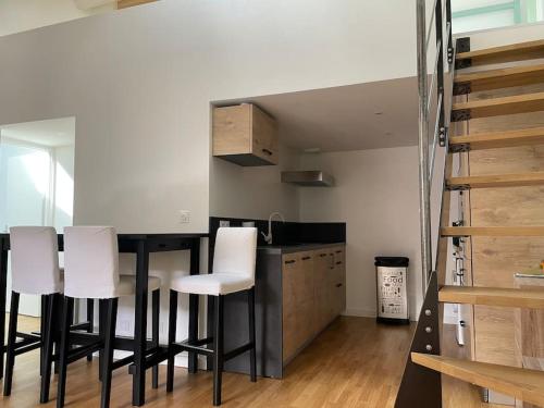 a kitchen with a table and some white chairs at Appartement atypique et fraîchement rénové in Saint-Vallier