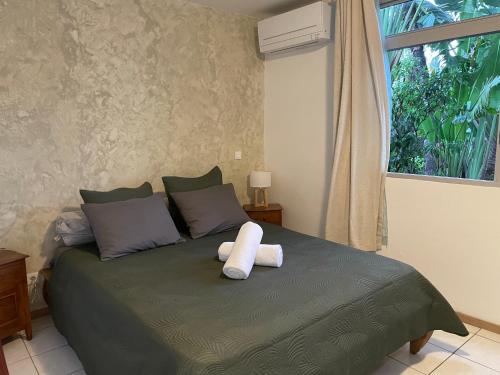 a bed with a towel on it with a window at Moehani Beach Lodge in Punaauia