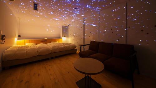 a bedroom with a bed and a couch and a star wall at リゾートホテル美萩 in Hagi