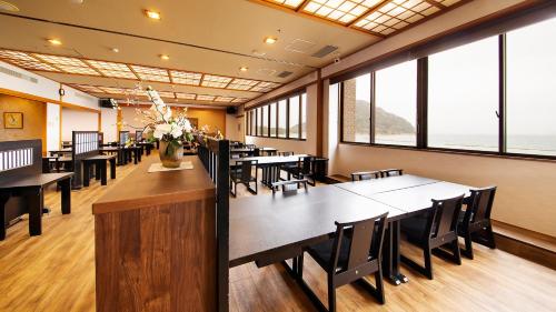 a dining room with tables and chairs and windows at リゾートホテル美萩 in Hagi