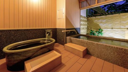 a bathroom with a toilet and a bath tub at リゾートホテル美萩 in Hagi