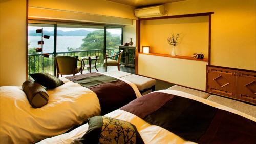 um quarto de hotel com três camas e uma varanda em 夕景の宿　海のゆりかご　萩小町 em Hagi