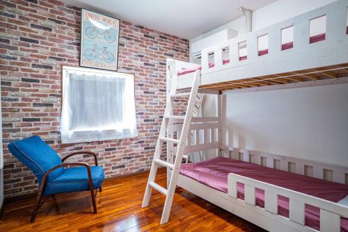 Pokój z 2 łóżkami piętrowymi, krzesłem i drabiną w obiekcie M&Unity w mieście Okinawa