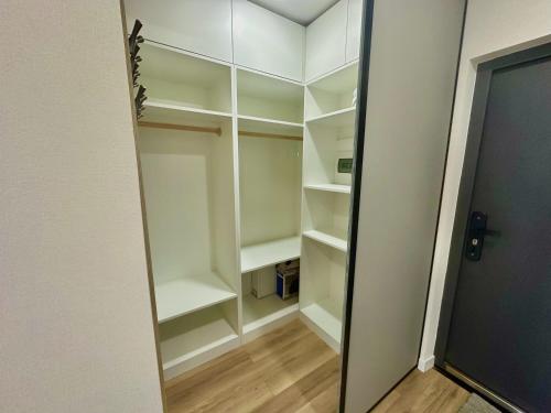 a walk in closet with white shelves and a door at Exclusive USA Embassy Proximity Apartments in Ulaanbaatar