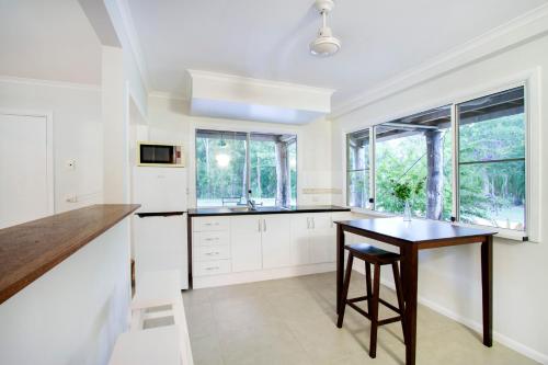 a kitchen with white cabinets and a wooden table at Airlie Beach Eco Cabins - Adults Only in Airlie Beach