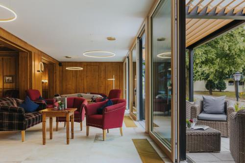 a living room with red chairs and a table at Hotel Drei Quellen Therme in Bad Griesbach