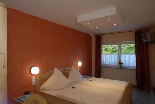 a bedroom with a bed with white sheets and a window at Hotel Eifeltor in Mechernich