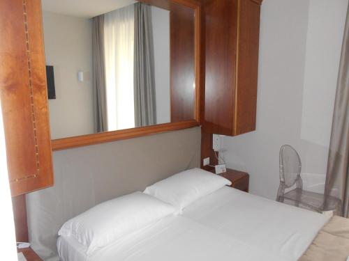 a bedroom with a white bed with a mirror at AFFITTACAMERE REGIO in Rome