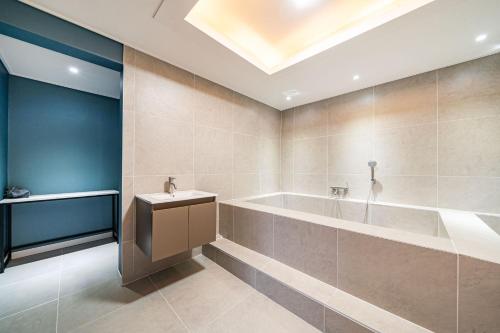 Sloth Hotel Gimhae في Gimhae: حمام مع حوض استحمام ومغسلة